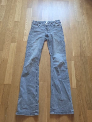 Grå bootcut jeans från Gina Tricot - Säljer ett par gråa bootcut jeans från Gina Tricot. Jeansen har klassisk femficksmodell, knapp och dragkedja framtill samt snygg tvättad look. Perfekta för dig som gillar en avslappnad men trendig stil.