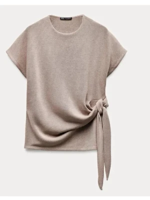 Beige topp med knyt från Zara - Stilren beige topp från Zara med korta ärmar och rund halsringning. Toppen har en snygg knytdetalj i sidan som ger en modern touch. Perfekt att matcha med både jeans och kjol för en trendig look. Kom privat för fler frågor eller bilder💞passar xs-S knappt använd