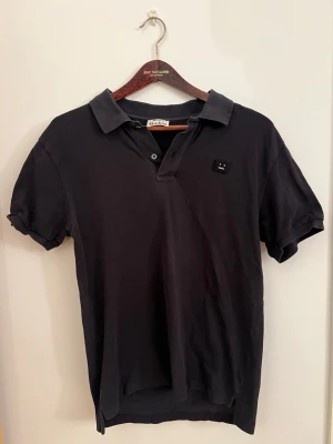 Svart pikétröja från Acne Studios - Piké från Acne. Sitter lite tajt vid ärmarna! Strl: M