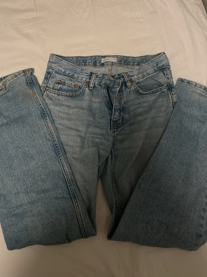 Ljusblå raka jeans från Levi's - Säljer ett par klassiska ljusblå jeans från Gina Tricot med rak passform och fem fickor. Jeansen har medel midja och är tillverkade i 100% bomull för en autentisk denimkänsla. Perfekta för en avslappnad och trendig look.