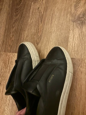 Svarta Axel Arigato sneakers i läder - Stilrena svarta sneakers från Axel Arigato i mjukt läder med vit sula. Vänster sko är lite nerknölat men inget man ser! 