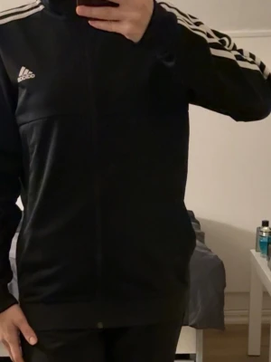 Svart Adidas träningsjacka - Säljer en svart träningsjacka från Adidas med dragkedja framtill.