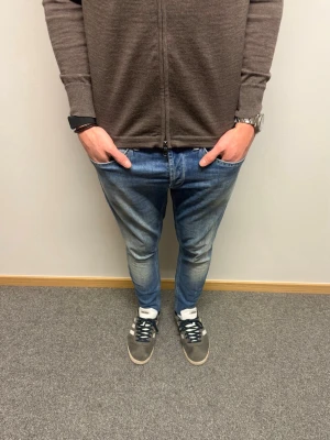 Dondup Jeans George - Dondup Jean i modell George - Populäraste jeansen på hela Plick.🤩 Nypris = 4000kr Super bra skick utan defekt (9/10) , Modellen har original slitningar från fabrik vilket är väldigt eftertraktat och populärt , (jeansen är uppsydda och passar därav modellen som är 175cm lång)