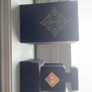 Initio Psychedelic Love parfym - Exklusiv parfym från Initio, Psychedelic Love. Flaskan är svart med guldiga detaljer och har en fyrkantig, lyxig design. Kommer i en elegant svart ask med dekorativt mönster i guld. Perfekt för dig som gillar unika och djupa dofter. 70/90ml kvar