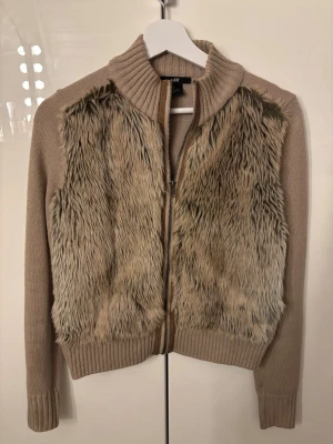 Beige päls cardigan - Snygg beige päls cardigan från H&M med mjuka fuskpälsdetaljer framtill och stickade partier på ärmar och rygg. Så cool och perfekt till afterski! Passar en xs-m