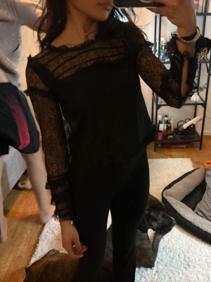 Svart spetsblus med volangdetaljer - Använder ej 