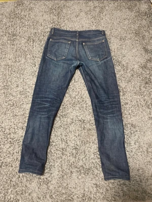 A.P.C. Selvedge jeans - Säljer ett par klassiska A.P.C. Petit New Standard jeans i mörkblå denim. Jeansen är raka med fem fickor, snygga kontrastsömmar och tillverkade i 100% bomull. Perfekt passform och stilren look för dig som gillar minimalistiskt mode. Tighta i änden av jeansen och kan vara lite svåra att få på