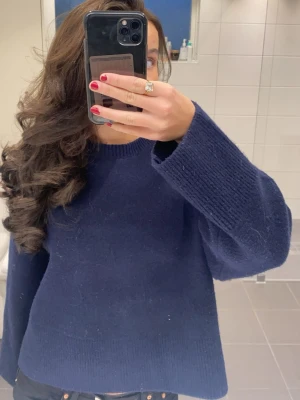 Mörkblå stickad tröja med vida ärmar - En stilren mörkblå stickad tröja som är lite vidare i modellen. Säljer då jag knappt användt den och den har bara hängt i garderoben