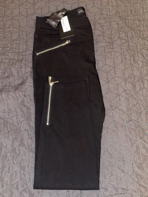 Svarta byxor  - Snygga svarta byxor från Stockh LM med  silverfärgade dragkedjor framtill. 