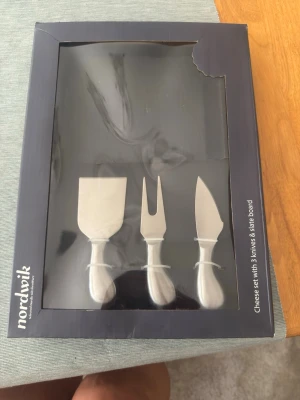 Ostset med tre knivar från Nordwik - Snyggt ostset från Nordwik med tre olika ostknivar och en skifferbricka. Knivarna har silverfärgade handtag och blad i rostfritt stål, perfekt för att skära och servera olika sorters ost. Levereras i originalförpackning.