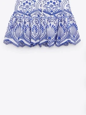 Vit och blå volangkjol med mönster - Säljer en skit snygg Kort kjol i vitt och blått med volanger och ett detaljerat, blommigt mönster. Säljer pga av att den är för liten 