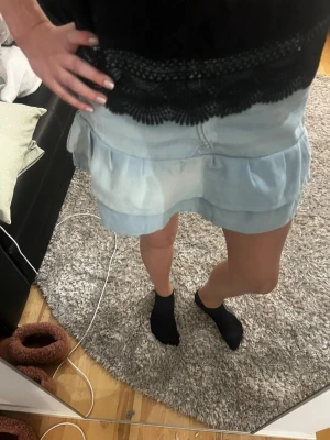 Ljusblå jeanskjol med volang - Supersöt ljusblå jeanskjol med volangkant och klassiska fickor fram. Kjolen har en kort modell och stängs med knapp och dragkedja. Perfekt för dig som gillar en avslappnad men trendig stil. Sydd själv