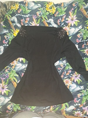 Svart off shoulder  långärmad topp med pärlor - Snygg svart långärmad topp med pärldetaljer på axlarna som ger en extra touch. Figurnära passform och mjukt material som känns skönt mot huden. Perfekt för dig som vill ha något stilrent men ändå med lite edge väldigt y2k och även off shoulder💕.