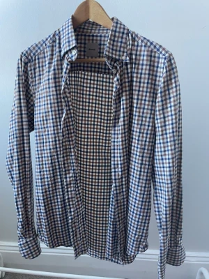 Rutig skjorta från Adverb - Snygg långärmad skjorta från Adverb med rutigt mönster i blått, brunt och vitt i storlek 39 (fanns ej i storleksbeskrivningen varav jag skrev S). Fint skick. Pris kan diskuteras 