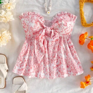 Blommig bandeau topp med rosett - Supersöt bandeau topp med orangeblommigt mönster. Volangkant upptill, stor knytrosett framtill. Helt slutsåld på hemsidan. 