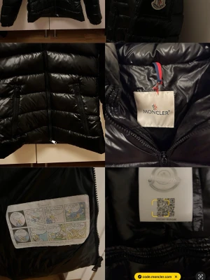 Svart dunjacka från Moncler - Säljer en svart, glansig dunjacka från Moncler med avtagbar huva och två dragkedjeförsedda fickor. Jackan har klassisk Moncler-logga på ärmen och innerfoder med serietidningsmotiv. 