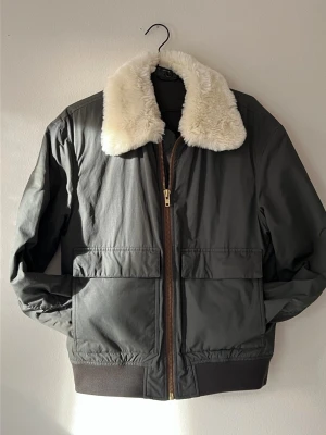 Filippa K technical flight bomber jacket - Militärgrön vatten- och vindavvisande bombarjacka från Filippa K i storlek 48 (motsvarande m).  Material:  * 52% nylon och 48% bomull, känt som “cotton-nylon flight cloth”/“cotton-nylon twill”, vindtåligt men luftigt.  Egenskaper:  * Täckt med Filippa Ks vattenavvisande medel (Bionic-Finish Eco).  * Tvättbar i maskin, medlet kan appliceras åter efter tvätt.  * Robust, kvalitativ konstruktion, kraftig löpare i mässing från YKK.  Skick * 9/10, enda felet är att ena fickflärpen saknar knapp. 