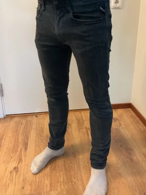 Replay jeans - Säljer ett par svarta slim fit jeans med klassisk femficksdesign och dragkedja. Jeansen har en modern, tight passform och är tillverkade i stretchigt denimtyg för extra komfort. Perfekta för dig som gillar en stilren och trendig look.