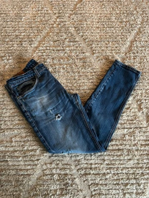 Dondup George jeans - Hej jag säljer ett par Dondup George jeans i riktigt snygg blå färg perfekt för dig som vill ha ett par kvalitetsjeans med grym passform. Nypris ≈3500kr, mitt pris 749kr.  Skick: 9/10 Storlek: W36 Midja: 43cm Lår: 26cm Ytterlängd: 102cm. Innerlängd: 77cm. Skriv gärna om du vill ha fler bilder eller har frågor!
