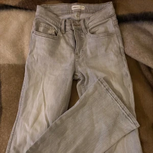 Ljusgråa bootcut jeans från Gina Tricot - Säljer ett par ljusgråa bootcut jeans från Gina Tricot med klassisk femficksdesign och hög midja. Jeansen har dragkedjegylf och är tillverkade i stretchigt denimtyg för en bekväm passform. Perfekta att matcha med sneakers eller boots.