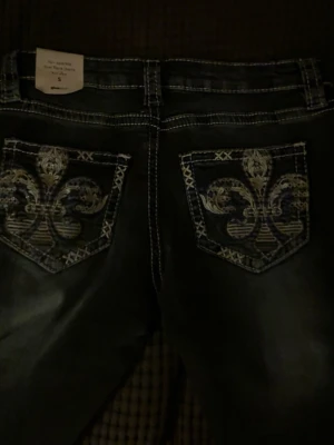 Lågmidjade mörkblå jeans - Säljer ett par mörkblå bootcut jeans från Gina tricot med snygg slitning och kontrastsömmar. Jeansen är aldrig använda endast testade.Storlek s 