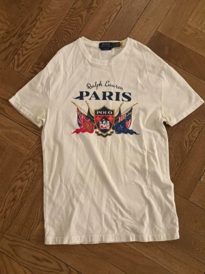 Polo Ralph Lauren T-Shirt - Vit t-shirt med tryck från Polo Ralph Lauren. Tecken på användning men bra skick (2 små hål längst ned, se sista bild). Nypris ca 1200 kr. Stl XS, priset kan diskuteras. 