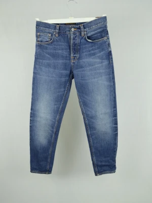 Nudie Jeans  - NUDIE JEANS Storlek : 28/32 Modell : Steady Eddie Mått : A = 38CM - B = 96CM Användning : Jeansen är i ett fint skick utan defekter Nypris : Cirka 2000SEK Modellen på bilden : 182CM och väger 78KG