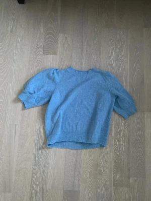 Ljusblå stickad tröja med puffärm - Säljer en ljusblå stickad tröja med trendiga puffärmar och ribbade muddar. Tröjan har rund halsringning och är något kortare i modellen. Perfekt för dig som vill ha en enkel men ändå snygg stickad topp.