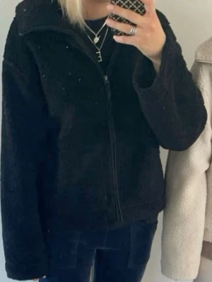 Svart teddyjacka från hm  - Mysig svart teddyjacka med hög krage och hel dragkedja framtill. Jackan har två stora fickor och är tillverkad i fluffigt, mjukt material som ger en avslappnad och trendig look. Perfekt för våren o sommaren. Skriv gärna frågor 