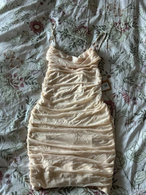 Oh polly klänning - Beige/aprikos klänning från Oh Polly storlek UK 12, motsvarar S. Lite öppen i ryggen.  Ny med prislapp! Stretchig innerklänning med ett mesh material på utsidan. 