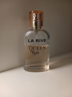 La Rive Queen of Life Eau de Parfum🌸🌷 - La Rive Queen of Life Eau de Parfum med en elegant transparent glasflaska och roséguldfärgat lock. Doften har en feminin och modern känsla, perfekt för dig som vill ha en fräsch och lyxig parfym i din samling. Flaskan har rundade former och stilren design. Väldigt sensuell och kvinnlig
