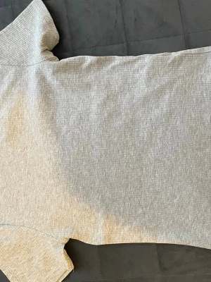 Ljusgrå ribbad topp - En stilren, ljusgrå topp med ribbad struktur. Toppen har korta ärmar som ger en clean och modern look. Perfekt att matcha med jeans eller kjol för en enkel men snygg outfit. Väldigt stretchig, skön och mjukt material. 