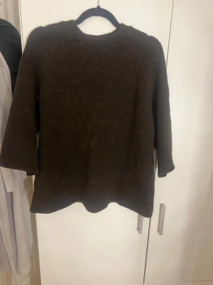 Mörkbrun stickad tröja Gina Tricot - Mysig mörkbrun stickad tröja från Gina Tricot i storlek M. Tröjan har rund halsringning, långa ärmar och en enkel, rak passform. Perfekt för kyliga dagar och lätt att matcha med olika outfits.