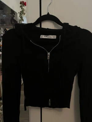 Svart croppad hoodie Faster Attire - Säljer en svart croppad hoodie från New Yorker  i storlek XS. Hoodien har dragkedja framtill, långa ärmar och en klassisk huva med snören. Perfekt till streetwear-looken och enkel att matcha med jeans eller kjol.