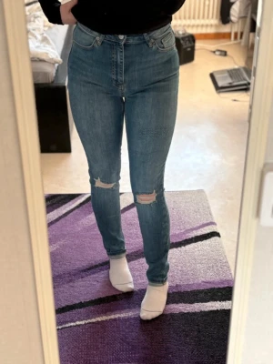Blå slim jeans med slitningar - Blåa jeans med slitningar & hål. Från NAKD! Jättefint skick! Vikt upp för lite för långa på mig som är 157! Finns på bild när ena sidan är uppvikt & den andra inte. Använt få gånger