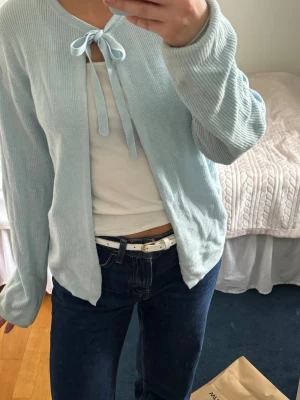 Ljusblå ribbad kofta med knytning  - Söt ljusblå kofta med knytning vid halsen! Andvänd fåtal gånger! 