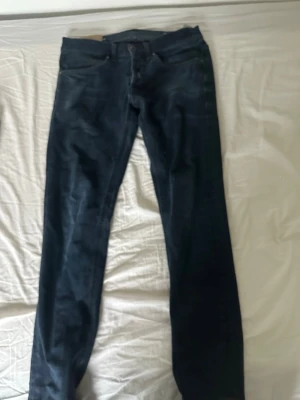 Mörkblå raka jeans - Säljer ett par mörkblå jeans med rak passform. Klassisk femficksmodell och knappgylf. Jeansen är i denim och har en stilren look som funkar till det mesta.pris kan diskutera!