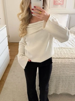 Off shoulder vit stickad tröja - Säljer en snygg off shoulder stickad tröja i krämvit färg. Tröjan har bred ribbstickning, långa ärmar och en bred, vikt krage som ger en trendig look. Perfekt för dig som gillar stilrena och moderna plagg.