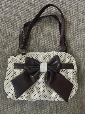 Prickig handväska med stor rosett - För fin nu till våren o sommaren! 🌸 Köpt i en vintage butik o de är inte riktigt min stil så säljer vidare den! 🥰 om ni har några frågor är de bara att höra av sig.  (Skickas samma dag eller dagen efter!) om ni är intresserade kom gärna med prisförslag!