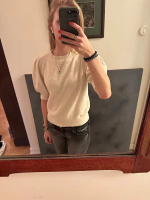 Vit puffärmad stickad tröja - Säljer en stilren vit stickad tröja med puffärmar och ribbade muddar vid ärmslut och nederkant. Tröjan har rund halsringning och är gjord i ett mjukt material som känns skönt mot huden. Perfekt för dig som gillar en enkel men trendig look.