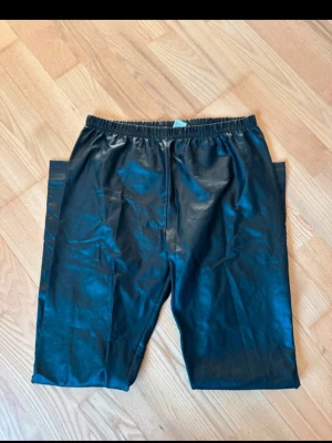 Svarta skinnleggins med resårmidja - Coola svarta leggins med rak passform och resår i midjan. Byxorna har en stilren look och är perfekta för dig som gillar en avslappnad men trendig stil. Materialet är klassisk manchester som ger en snygg struktur och känsla.