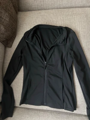 Svart ziptröja med hög krage - Snygg svart ziptröja med hög krage och långa ärmar. Tröjan har en figurnära passform och är tillverkad i ett stretchigt material som känns sportigt och bekvämt. Perfekt att slänga på sig över en t-shirt eller träningstopp.💞💞💕 