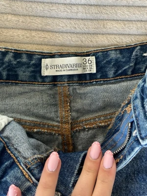 Blå jeanskjol från Stradivarius - Säljer en klassisk blå jeanskjol från Stradivarius i storlek 36. Kjolen har bakfickor med snygga kontrastsömmar. Perfekt att matcha med en enkel topp eller hoodie.