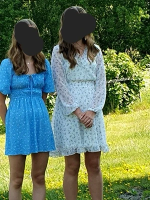 Vit blommig klänning - Säljer min jättefina sommarklänning då den inte används. Den är i nyskick, har bara använts en gång på min skolavslutning! Klänningen är vit med blå/bruna blommor! 💕