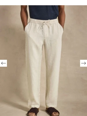 John Henric Linnebyxor  - Snygga och avslappnade linnebyxor i beige med rak passform och elastisk midja med dragsko. Byxorna har sidfickor och en bakficka, perfekta för en chill och stilren look. Tillverkade i svalt linnematerial som passar perfekt till varma dagar.