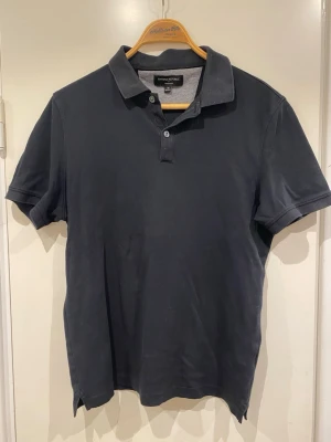 Svart pikétröja Banana Republic - Klassisk svart pikétröja från Banana Republic med korta ärmar och krage. Storlek M. 