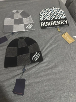 Burberry mössa med monogram och logga - Säljer en stickad mössa från Burberry med ett grafiskt monogrammönster i vitt, svart och ljusblått. Stor Burberry-logga framtill på uppvikt kant. Klassisk beanie-modell i mjukt material, perfekt för dig som gillar exklusiva accessoarer. 300 för en mössa annars pris kan diskuteras 