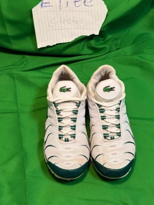 Nike Air Max sneakers vit/grön x Lacoste - Nike Air Max sneakers i vitt och grönt med mesh och syntetmaterial. Snygga detaljer med gröna vågiga linjer, synlig Air Max-dämpning i sulan och snörning. Klassisk Nike Swoosh på sidan och broderad krokodil på plösen för extra stil.Liknande modell som originalet!