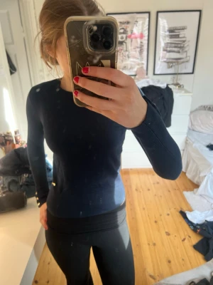 Mörkblå stickad tröja från Lindex - Snygg mörkblå stickad tröja från Lindex med rund halsringning och långa ärmar. Tröjan har ribbade muddar vid ärmslut och nederkant samt en liten metallogo vid höften. Perfekt till jeans eller kjol för en clean look.