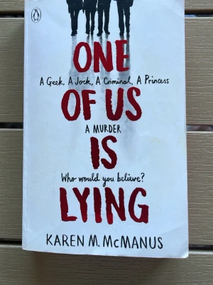 One of Us Is Lying av McManus - En spännande ungdomsroman på engelska av Karen M. McManus. Omslaget är vitt med röd och svart text samt siluetter av fem personer. Boken handlar om fem elever, hemligheter och ett mordmysterium. Perfekt för dig som gillar thrillers och high school-draman.
